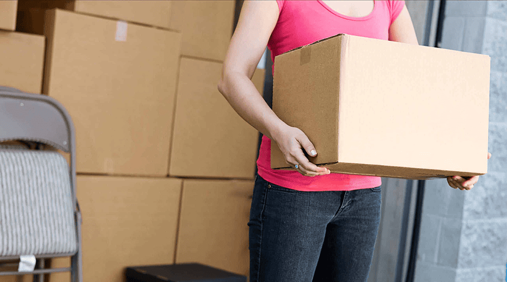 A mover demonstrates 5 moving tips while holding a box in front of a moving truck.